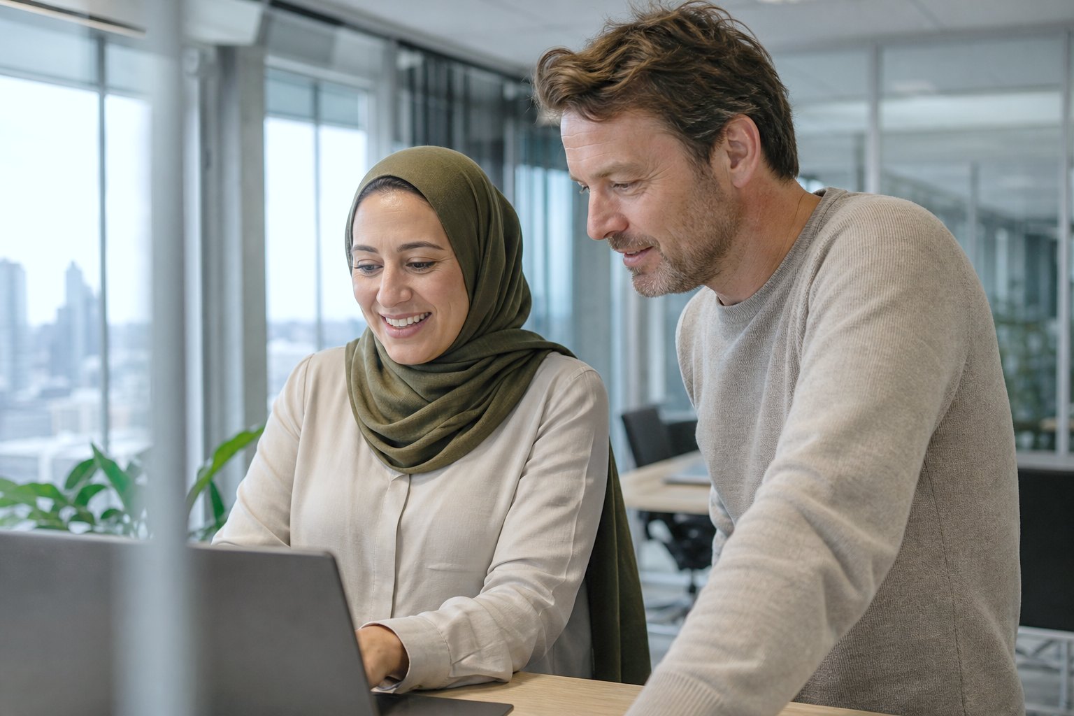 Twee collega’s samen achter één laptop aan een lichte werktafel