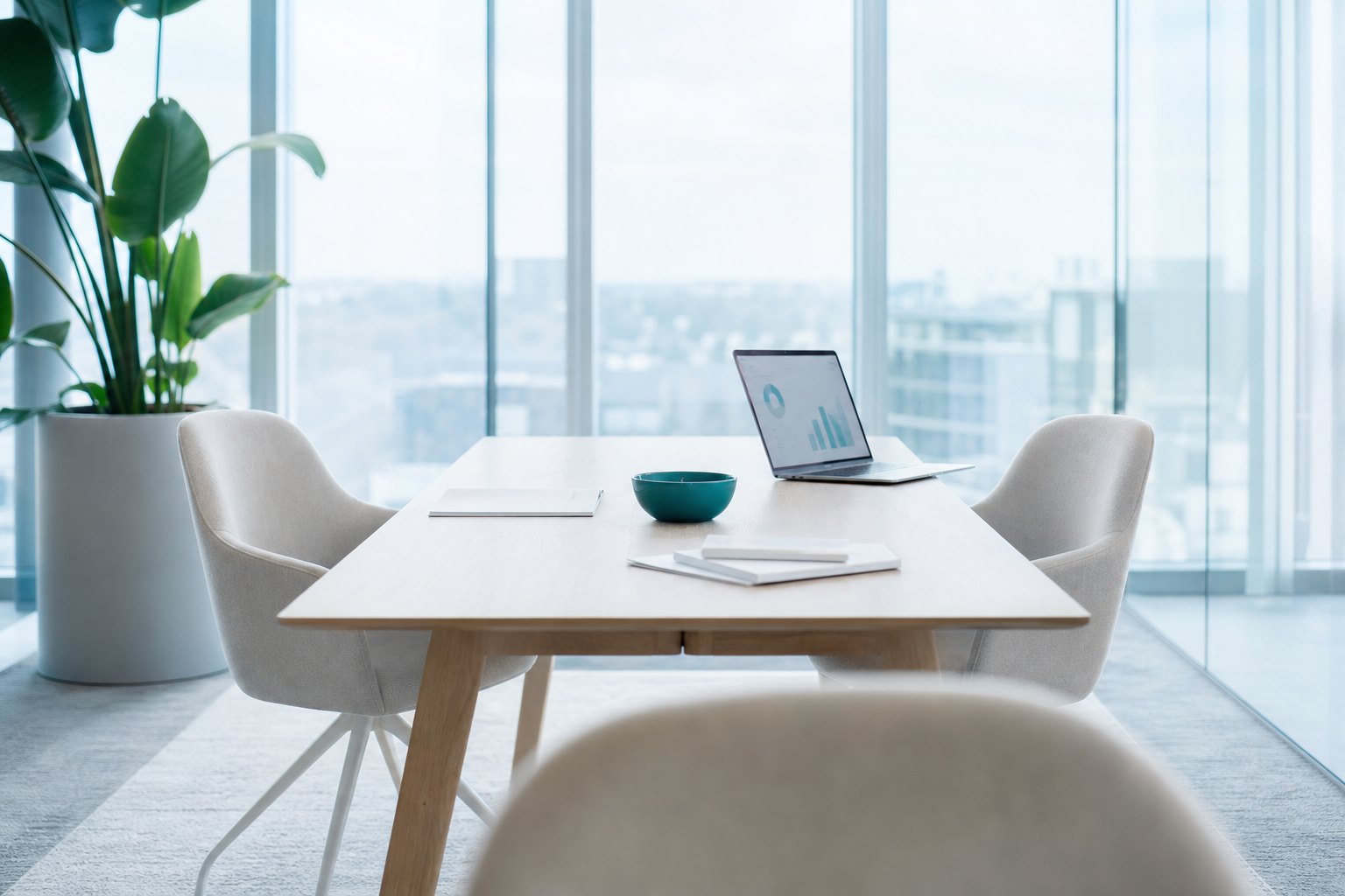 Overlegtafel met twee stoelen tegenover elkaar, documenten en een laptop